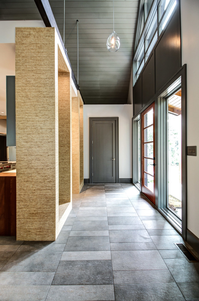 Ejemplo de distribuidor actual de tamaño medio con paredes beige, suelo de pizarra, puerta simple y puerta de madera oscura