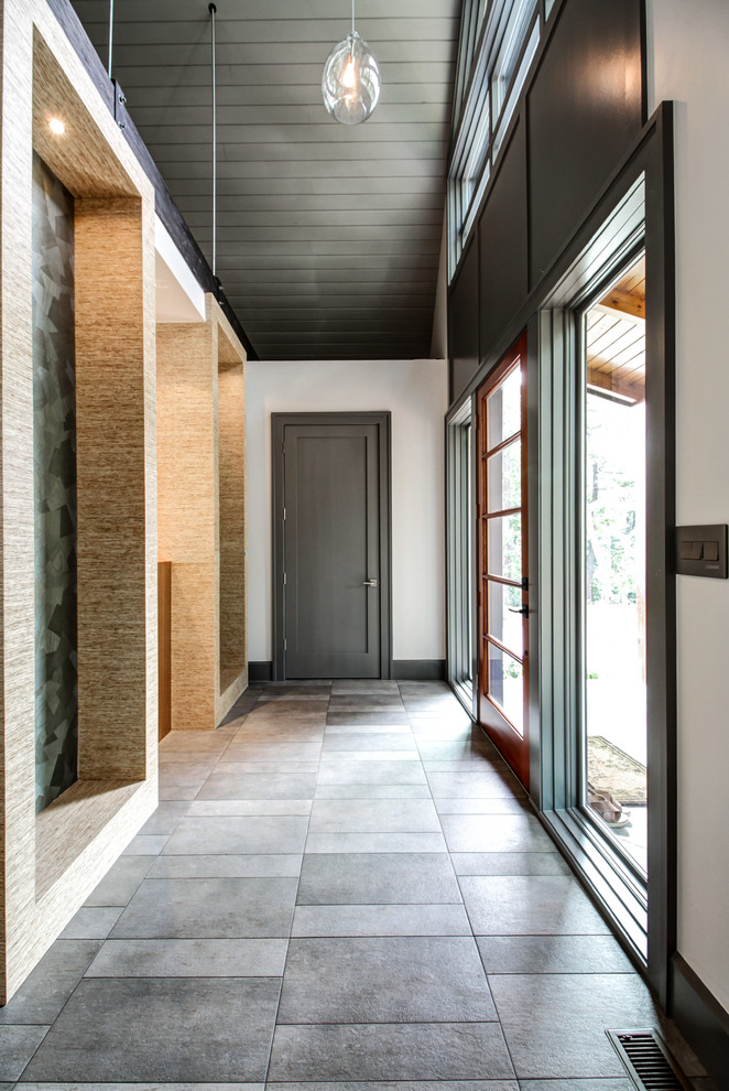 На фото: фойе среднего размера в современном стиле с бежевыми стенами, полом из сланца, одностворчатой входной дверью и входной дверью из темного дерева