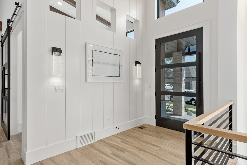 Foto på en stor funkis foajé, med vita väggar, klinkergolv i porslin, en enkeldörr, en svart dörr och beiget golv