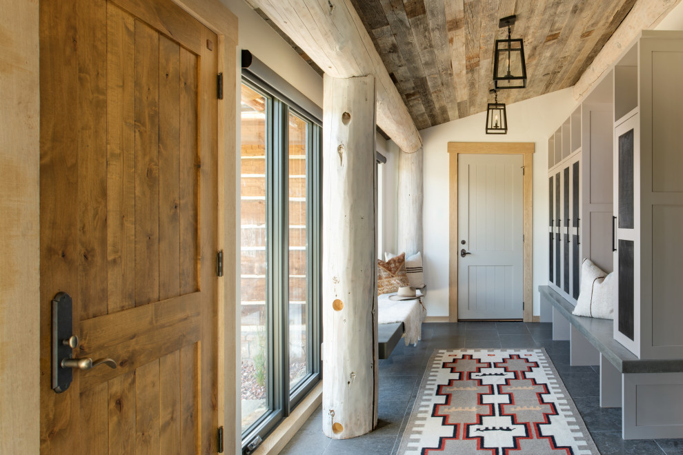 Inspiration pour une entrée chalet de taille moyenne avec un vestiaire, un mur blanc, une porte simple, un sol gris et un plafond en bois.
