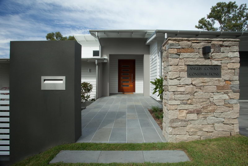 Réalisation d'une grande porte d'entrée design avec un mur gris, une porte pivot et une porte en bois brun.