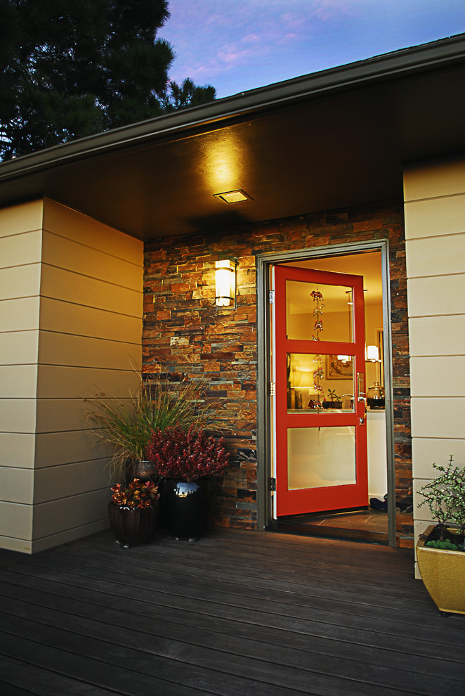 Aménagement d'une porte d'entrée rétro de taille moyenne avec parquet clair, une porte simple et une porte rouge.