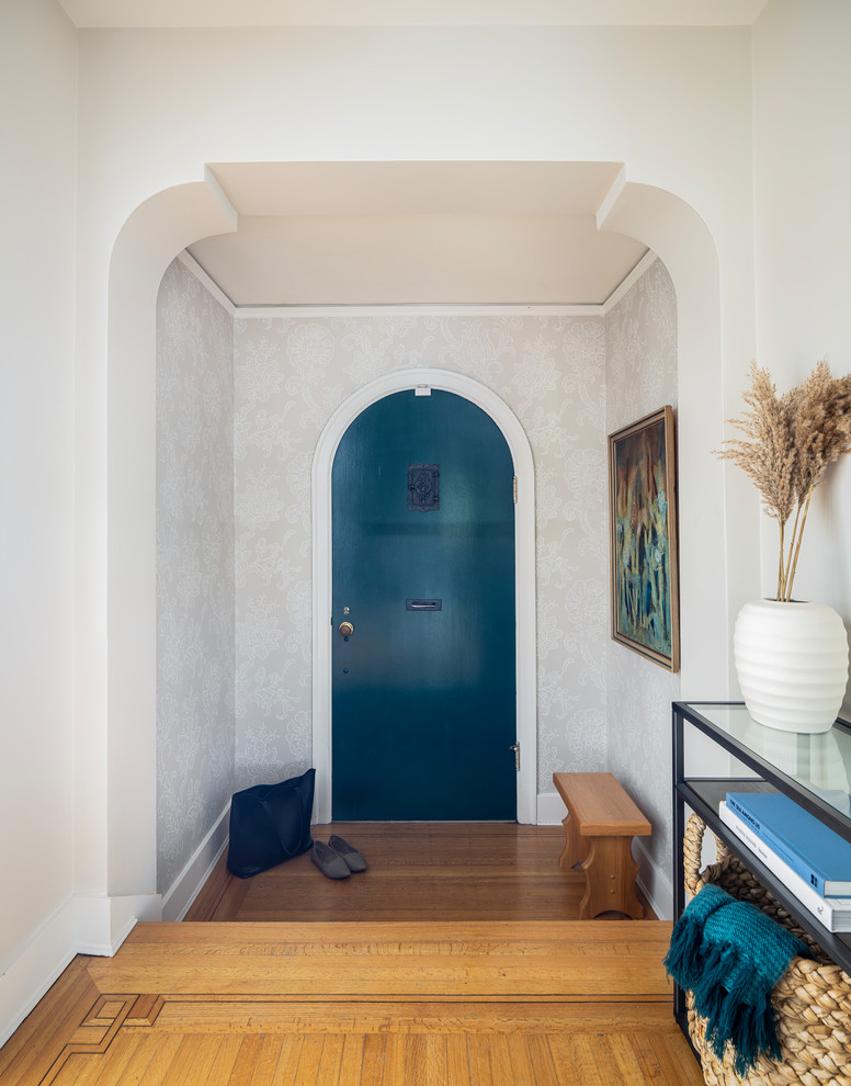 Idée de décoration pour une entrée tradition avec un couloir, un mur blanc, un sol en bois brun, une porte simple, une porte bleue et un sol marron.