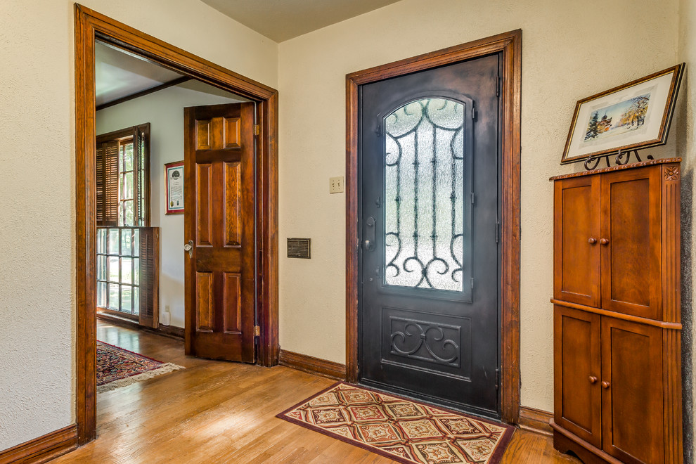 На фото: входная дверь среднего размера в классическом стиле с бежевыми стенами, светлым паркетным полом, одностворчатой входной дверью, черной входной дверью и коричневым полом с