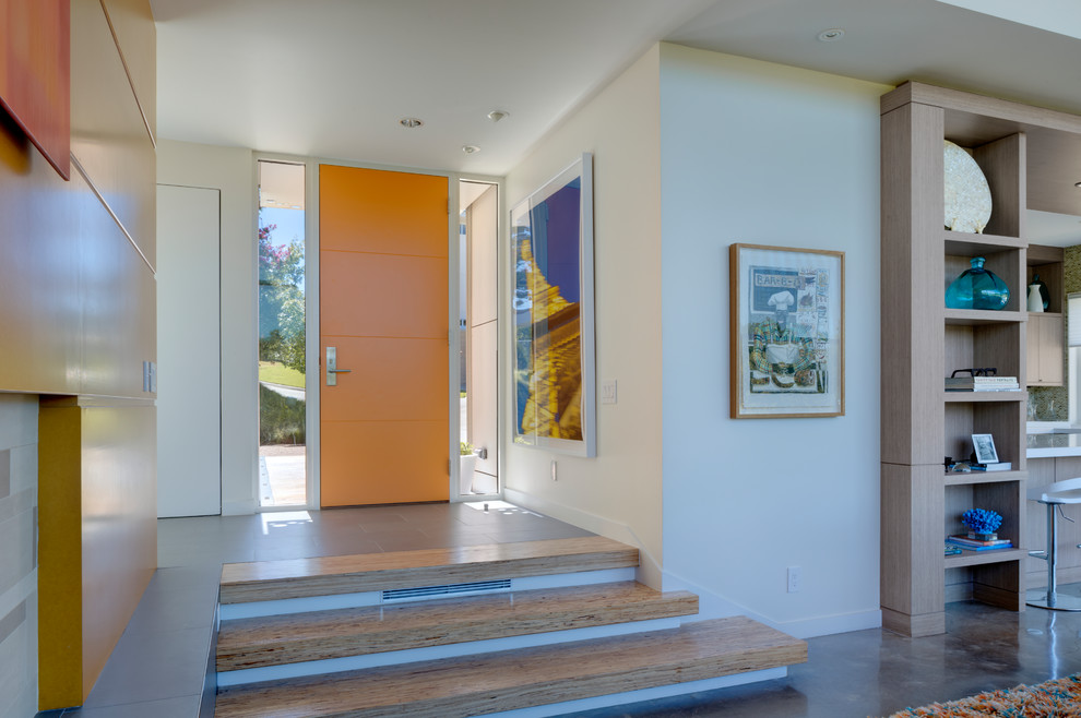 Modern inredning av en mellanstor ingång och ytterdörr, med vita väggar, betonggolv, en enkeldörr, en orange dörr och brunt golv