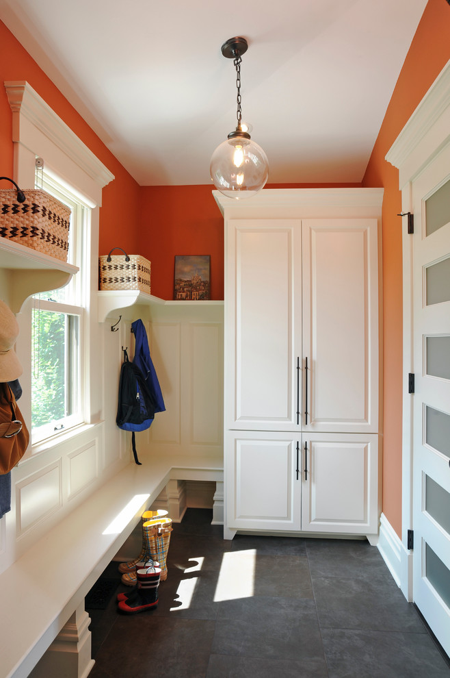 Réalisation d'une entrée tradition de taille moyenne avec un vestiaire, un mur orange, un sol en ardoise et une porte blanche.