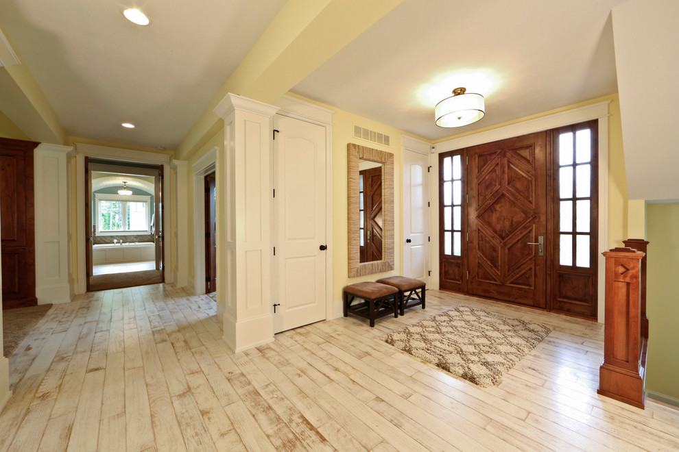 Großes Klassisches Foyer mit gelber Wandfarbe, hellem Holzboden, Einzeltür, hellbrauner Holzhaustür und weißem Boden in Grand Rapids