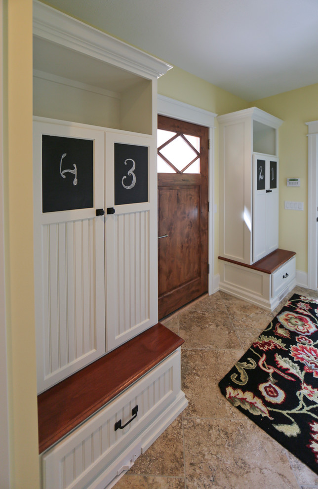 Exemple d'une grande entrée chic avec un vestiaire, un mur jaune, un sol en marbre, une porte simple et une porte en bois brun.