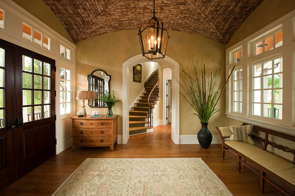 Klassischer Eingang mit beiger Wandfarbe, braunem Holzboden, Doppeltür und dunkler Holzhaustür in Charleston