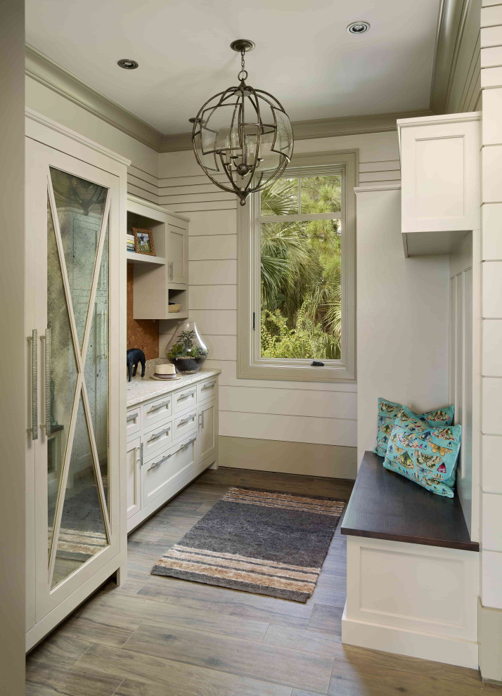 Example of a beach style medium tone wood floor and shiplap wall mudroom design in Charleston with white walls