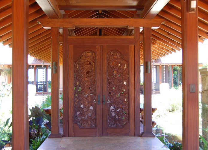 Cette image montre une porte d'entrée ethnique avec une porte double et une porte en bois brun.