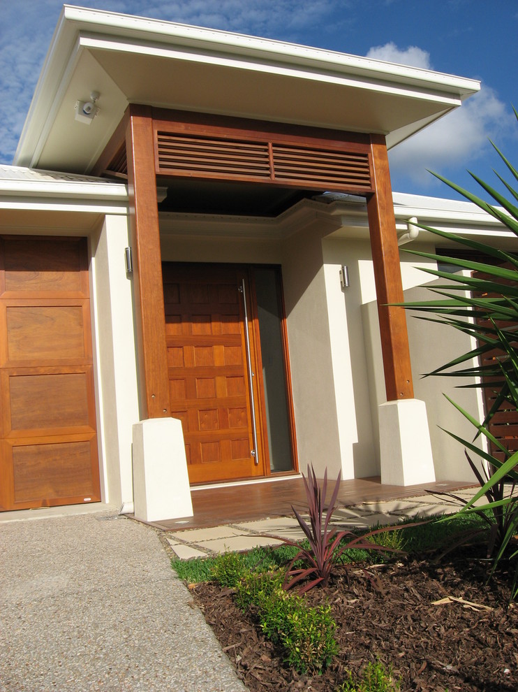 Imagen de puerta principal moderna con paredes blancas, suelo de madera en tonos medios, puerta pivotante y puerta de madera en tonos medios