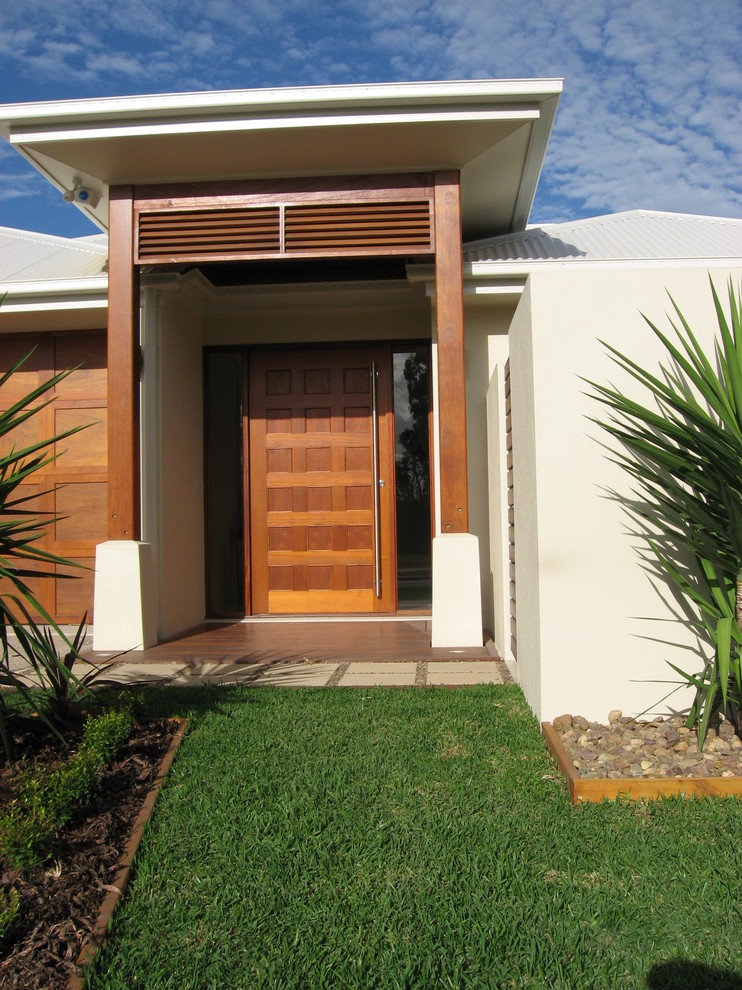 Modelo de puerta principal moderna con paredes blancas, suelo de madera en tonos medios, puerta pivotante y puerta de madera en tonos medios