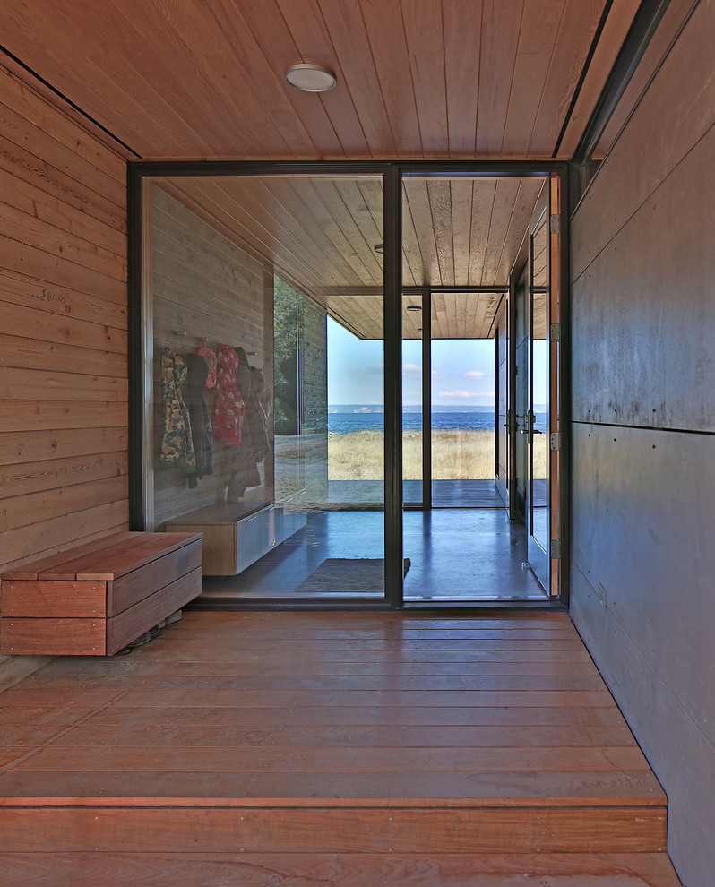 Cette image montre une porte d'entrée design de taille moyenne avec une porte simple, une porte en verre, un mur marron, sol en béton ciré et un sol gris.