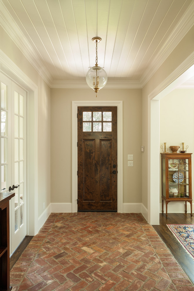 Idee per un corridoio chic con pavimento in mattoni, una porta singola e una porta in legno scuro