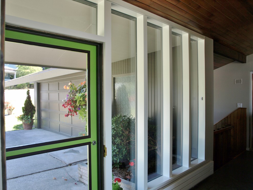 Bild på en mellanstor 50 tals ingång och ytterdörr, med vita väggar, skiffergolv, en enkeldörr och en grön dörr