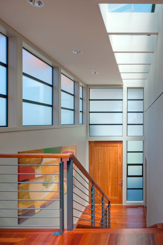Moderner Eingang mit Korridor, grauer Wandfarbe, braunem Holzboden, Drehtür und hellbrauner Holzhaustür in Seattle