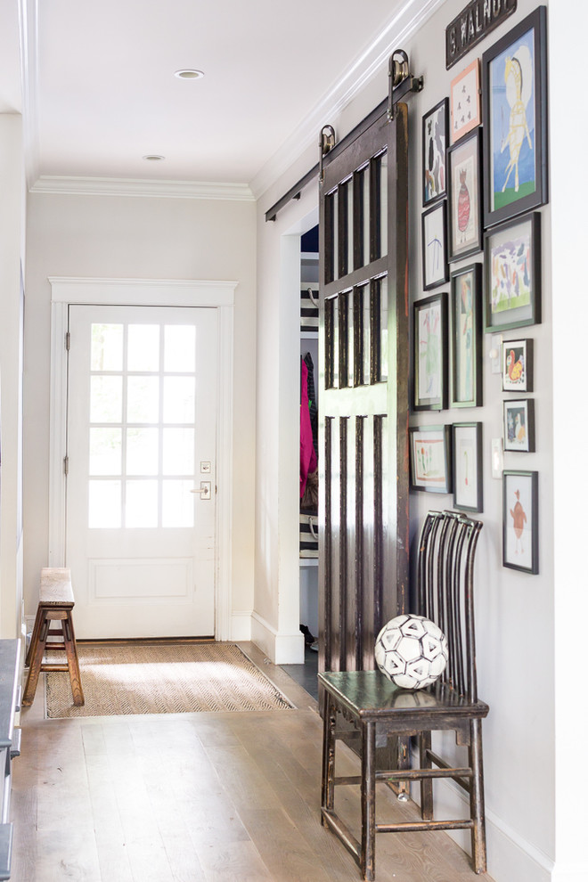 Ispirazione per un corridoio chic con pareti grigie, pavimento in legno massello medio, una porta singola e una porta in vetro