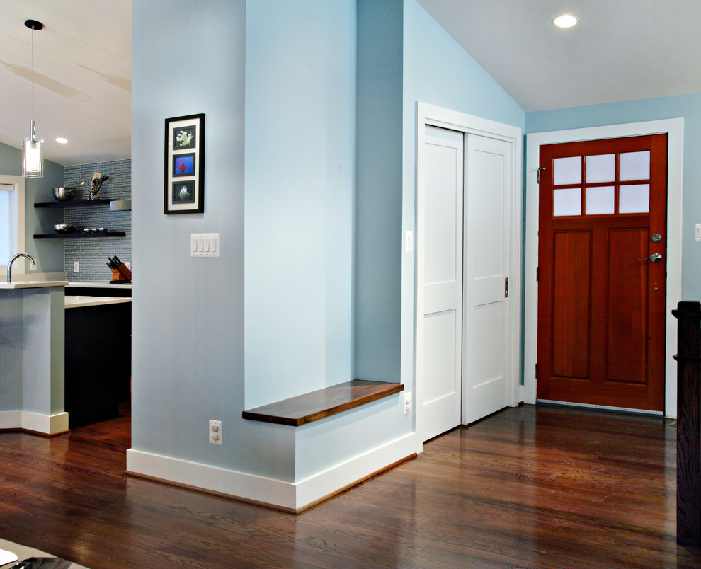 Cette photo montre une petite porte d'entrée tendance avec une porte simple, une porte en bois brun, un mur bleu et parquet foncé.