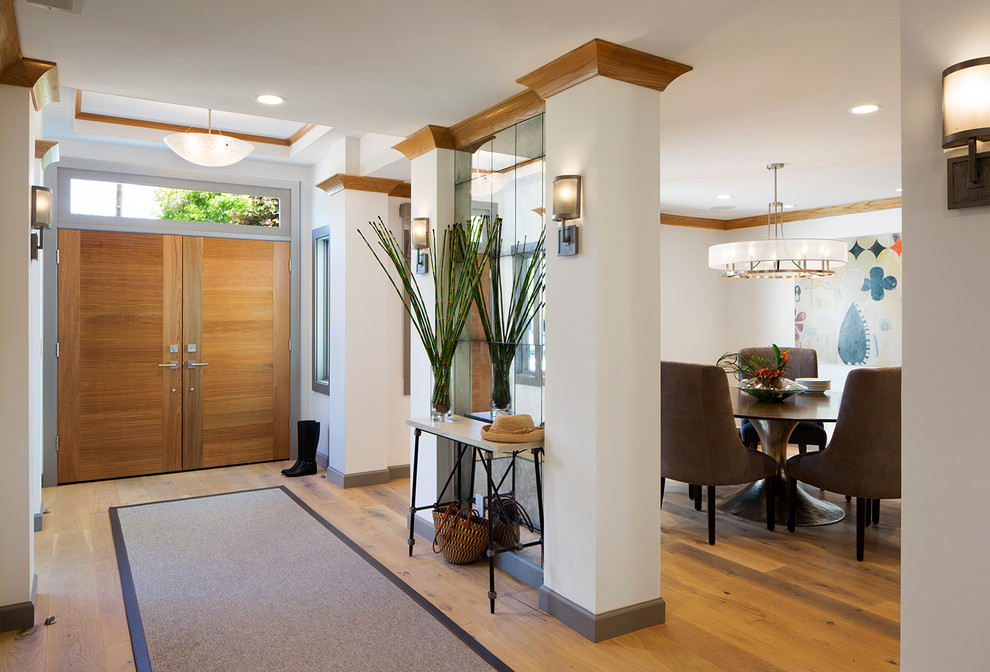 This is an example of a classic foyer in San Francisco with light hardwood flooring, a double front door and a light wood front door.