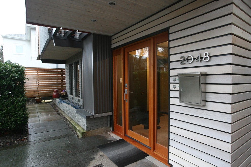 Cette image montre une grande porte d'entrée design avec un mur gris, sol en béton ciré, une porte simple et une porte en verre.
