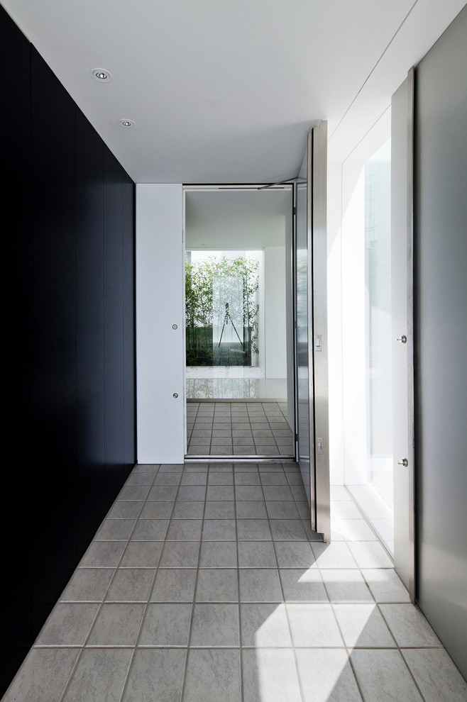 Пример оригинального дизайна: большая узкая прихожая в стиле модернизм с белыми стенами, полом из керамогранита, одностворчатой входной дверью, металлической входной дверью и серым полом