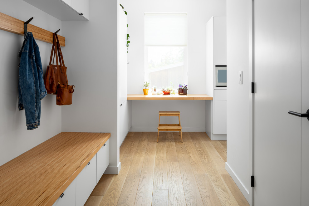This is an example of a medium sized modern boot room in Other with white walls, medium hardwood flooring, a single front door, a grey front door and brown floors.