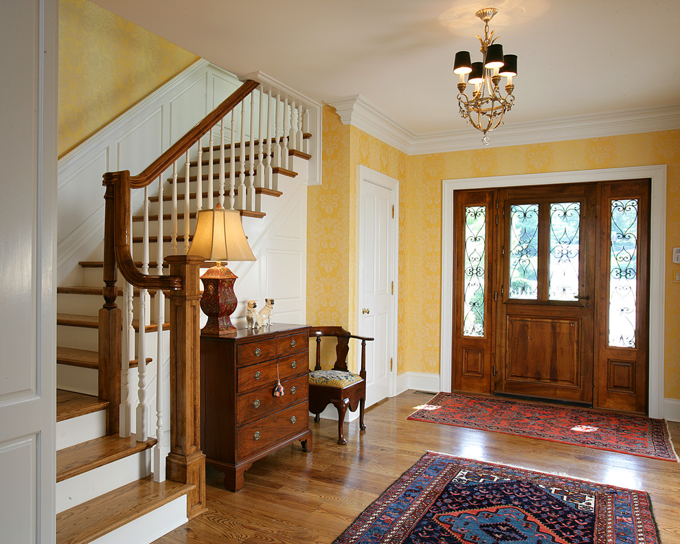 Aménagement d'une porte d'entrée classique de taille moyenne avec un mur jaune, un sol en bois brun, une porte hollandaise et une porte en bois foncé.