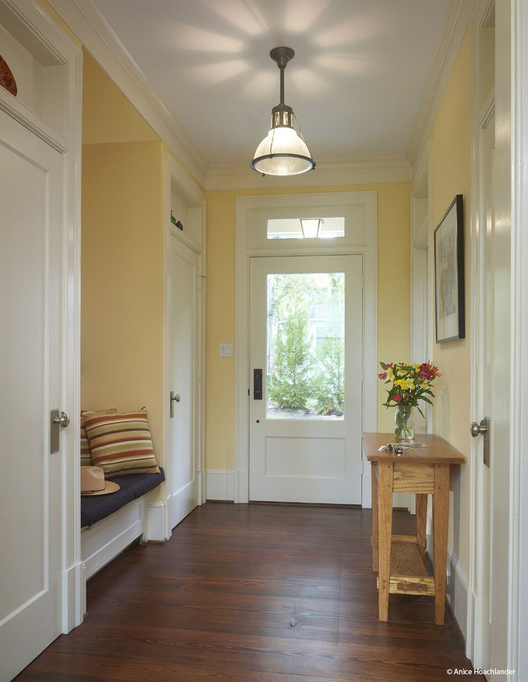 Ejemplo de hall clásico renovado de tamaño medio con paredes amarillas, suelo de madera oscura, puerta simple y puerta blanca