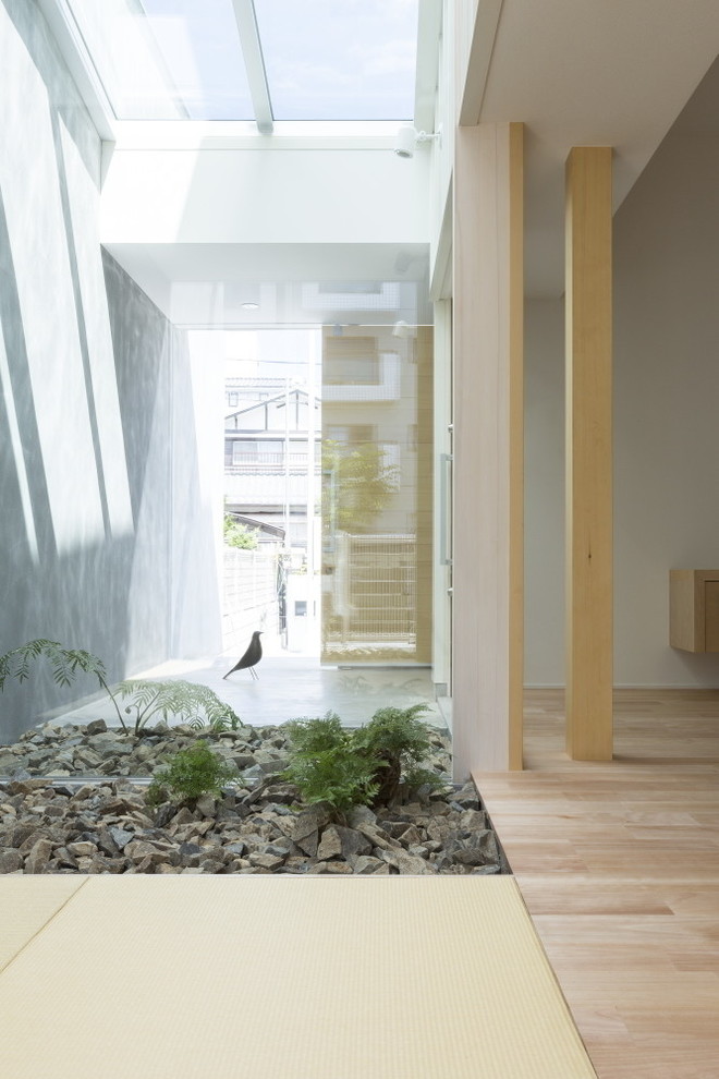 На фото: узкая прихожая среднего размера в скандинавском стиле с белыми стенами, бетонным полом, раздвижной входной дверью, входной дверью из светлого дерева и серым полом