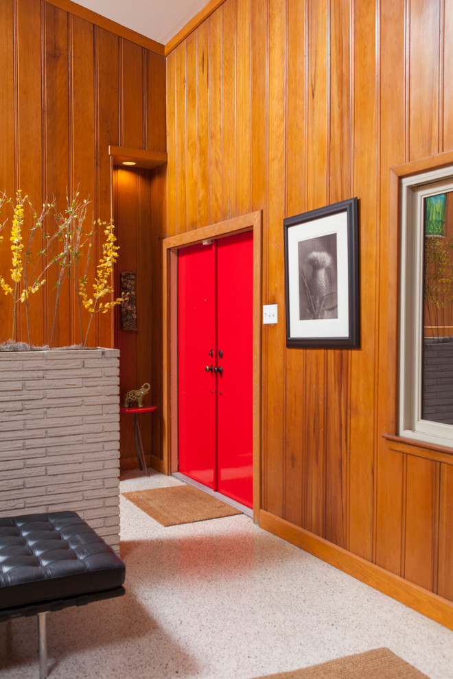 Cette image montre une entrée vintage avec une porte double et une porte rouge.