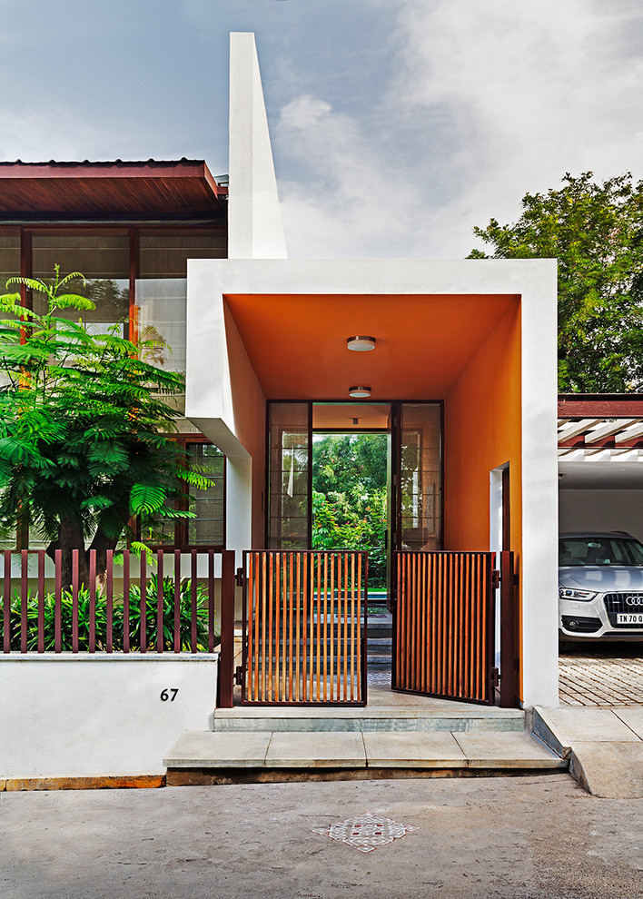 Réalisation d'une porte d'entrée design avec un mur orange, sol en béton ciré, un sol gris et une porte simple.