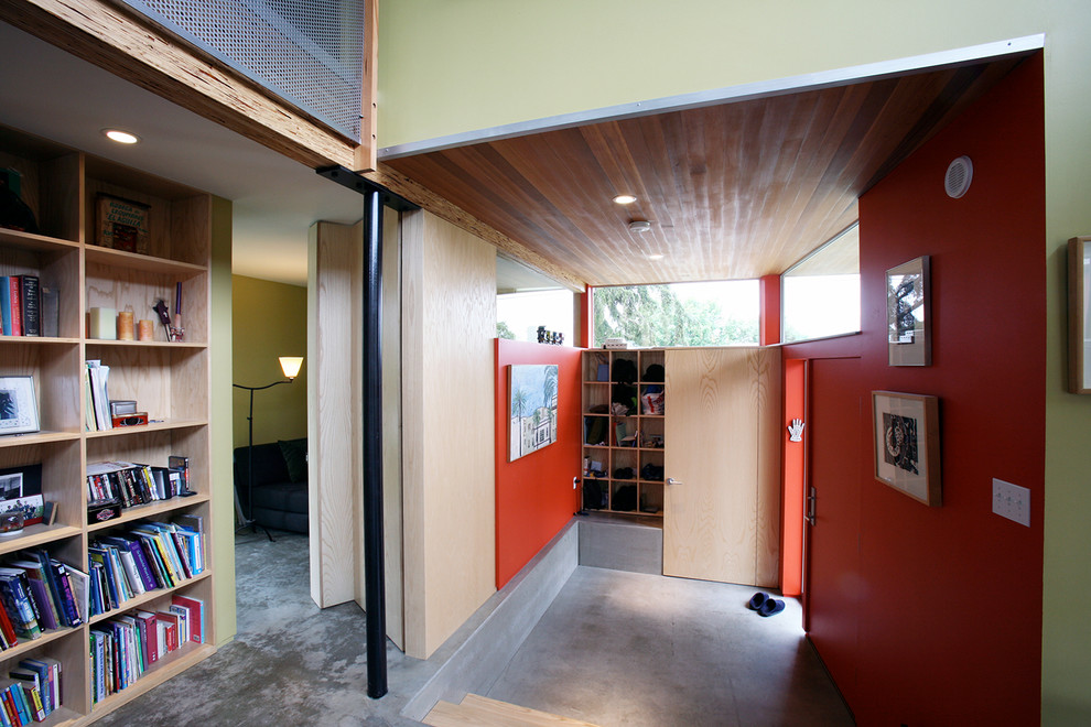 Photo of a small industrial boot room in Seattle with red walls, concrete flooring, a single front door and a red front door.