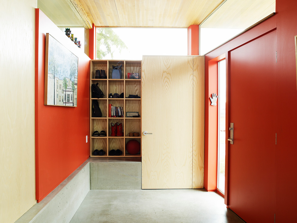Inspiration pour une entrée urbaine avec un vestiaire, un mur rouge, sol en béton ciré, une porte rouge et une porte simple.
