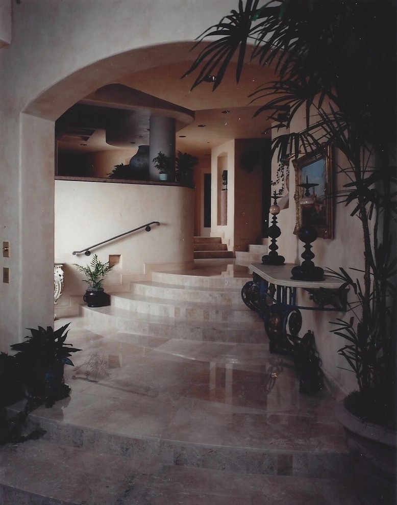 Imagen de entrada mediterránea grande con paredes beige, suelo de mármol y suelo marrón