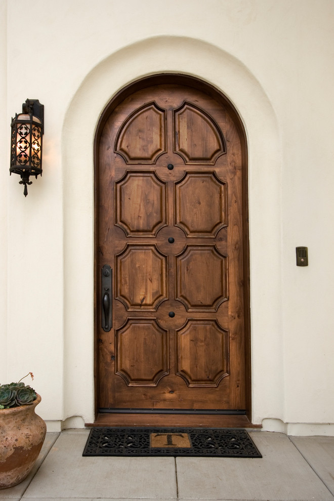 Ejemplo de puerta principal mediterránea grande con paredes beige, puerta simple, puerta de madera en tonos medios y suelo gris