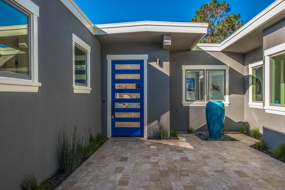 На фото: входная дверь среднего размера в стиле неоклассика (современная классика) с одностворчатой входной дверью, синей входной дверью, серыми стенами, полом из травертина и бежевым полом с