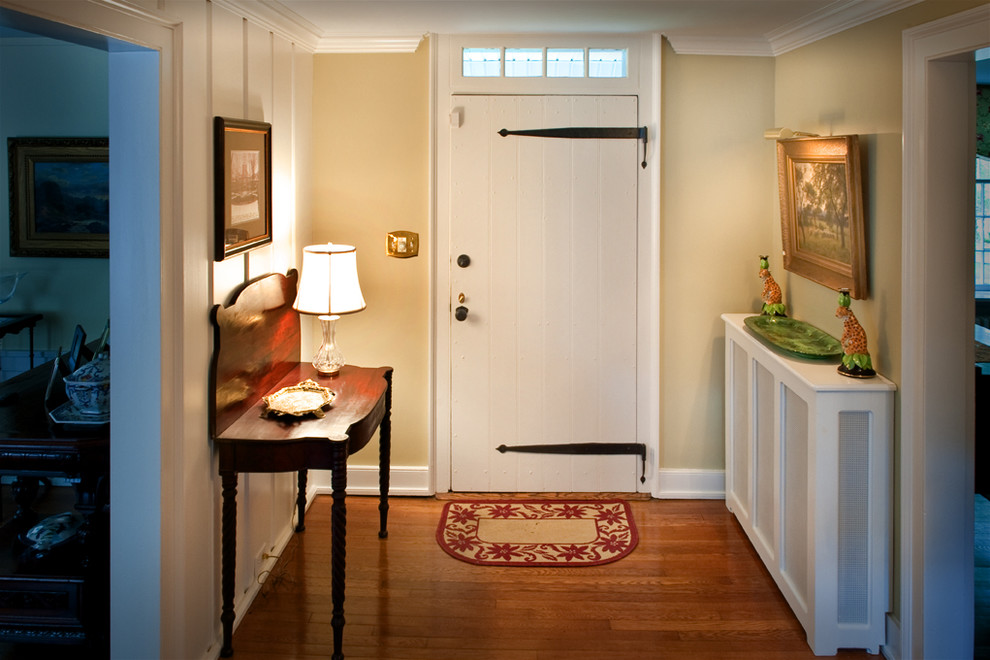 На фото: фойе среднего размера в классическом стиле с желтыми стенами, паркетным полом среднего тона, одностворчатой входной дверью, белой входной дверью и коричневым полом с