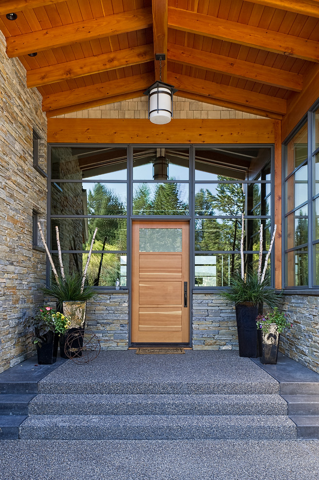 Photo of a contemporary front door in Calgary with a single front door, brown walls, carpet, a medium wood front door and grey floors.