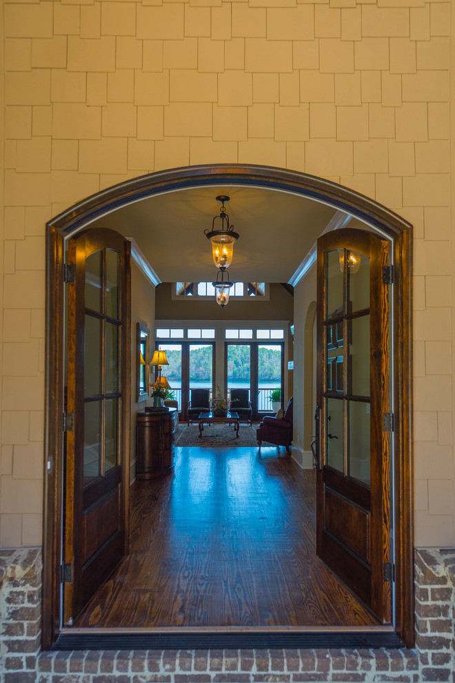 Modelo de puerta principal tradicional con suelo de madera en tonos medios, puerta doble, paredes blancas y puerta de vidrio