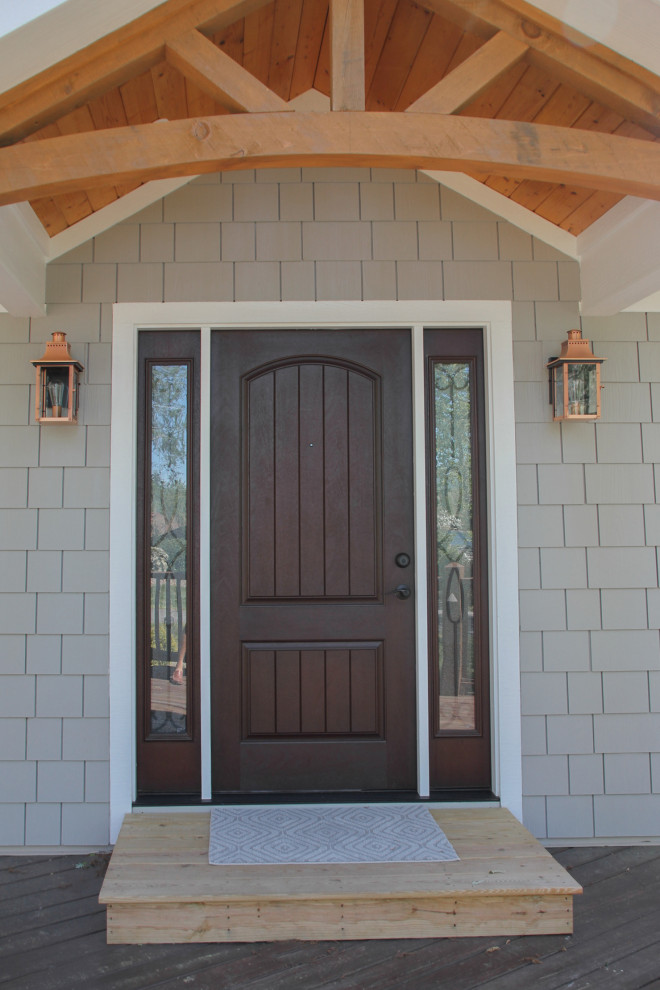 Cette image montre une petite porte d'entrée marine avec une porte simple, une porte en bois foncé et un mur gris.