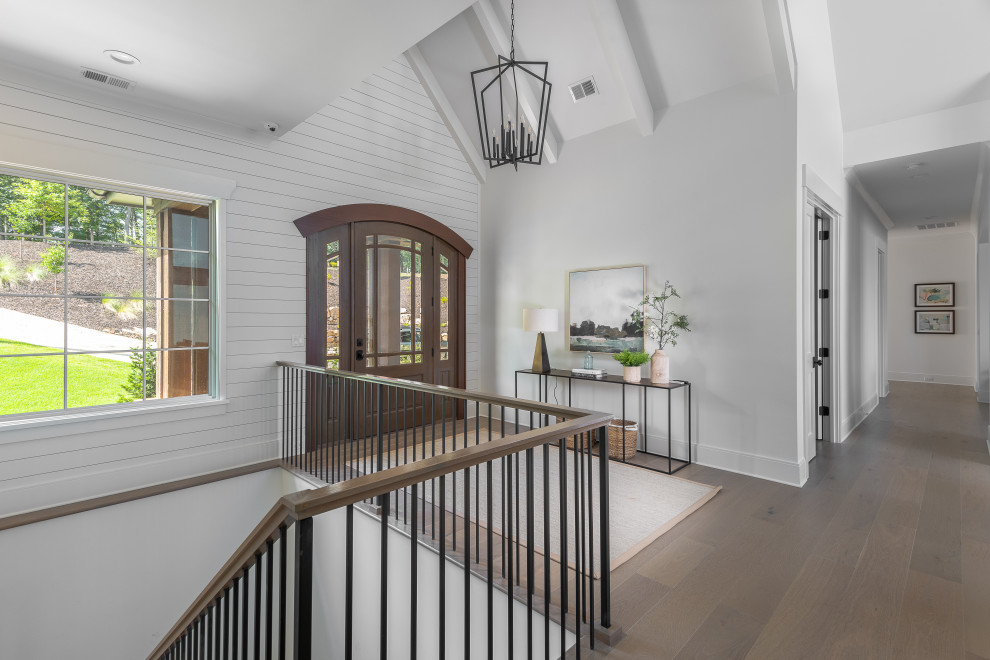 Photo of a traditional entrance in Other with white walls, dark hardwood flooring, a single front door, a medium wood front door, brown floors, exposed beams, a vaulted ceiling and tongue and groove walls.