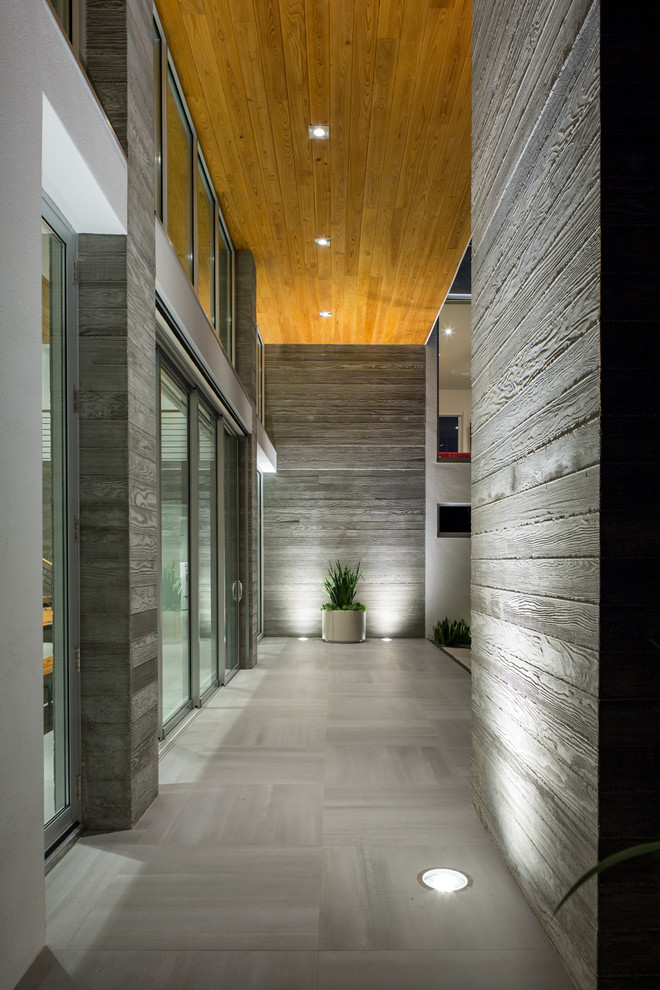 Стильный дизайн: большая узкая прихожая в стиле модернизм с белыми стенами, бетонным полом, одностворчатой входной дверью и стеклянной входной дверью - последний тренд