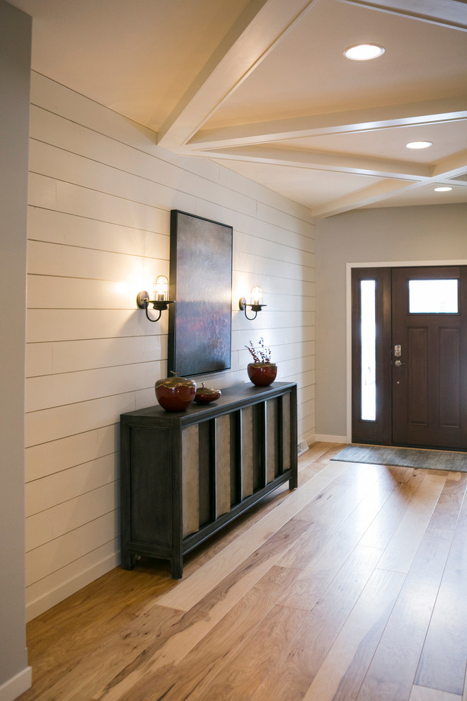 This is an example of an industrial entrance in Other with white walls, light hardwood flooring, a single front door, a dark wood front door and beige floors.
