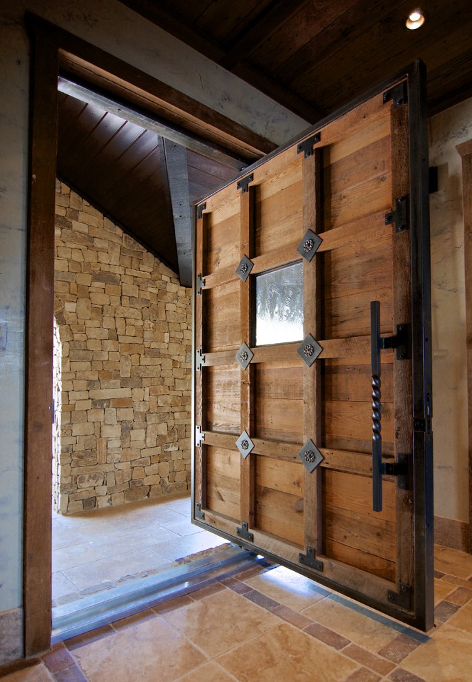 Réalisation d'une grande porte d'entrée chalet avec une porte pivot et une porte en bois brun.