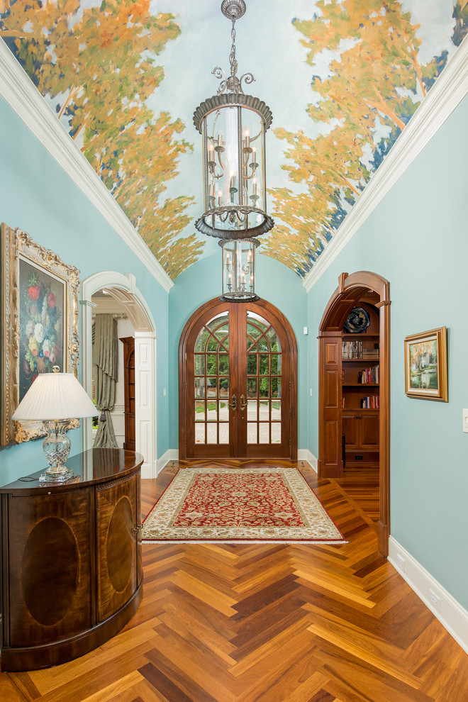 Foto di un corridoio tradizionale con pareti blu, pavimento in legno massello medio, una porta a due ante e una porta in vetro