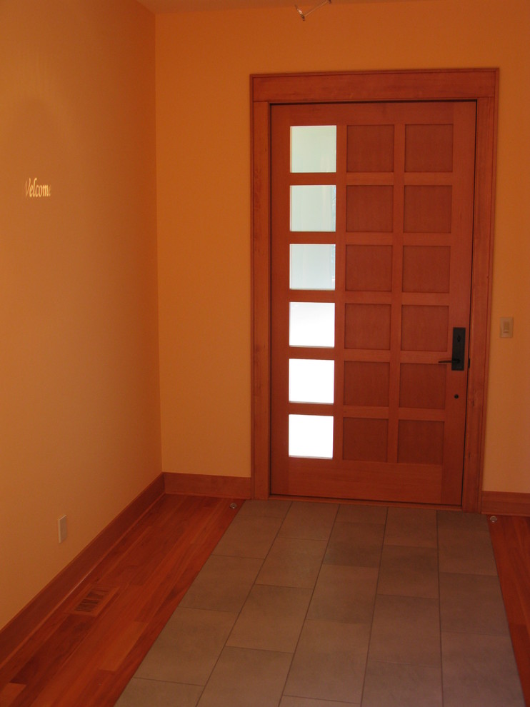 Idées déco pour une entrée moderne avec un mur jaune, un sol en bois brun, une porte simple et une porte en bois brun.