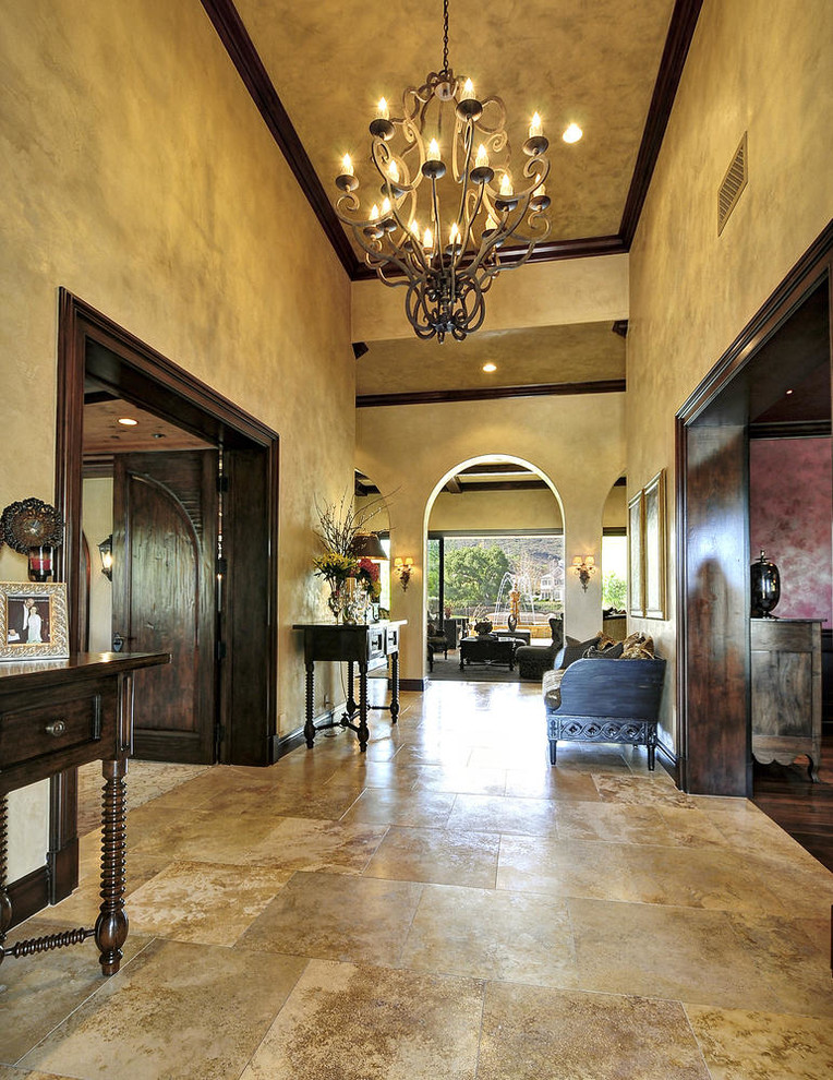Huge tuscan ceramic tile entryway photo in Los Angeles with beige walls and a dark wood front door
