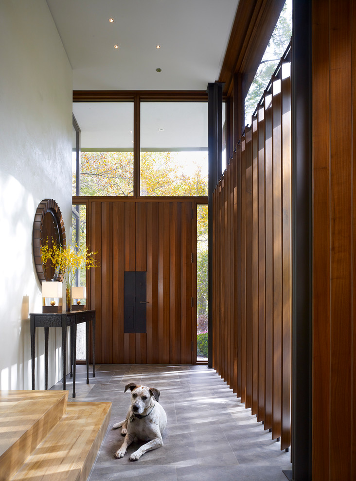 Idee per un grande corridoio design con pareti bianche, una porta a due ante, una porta in legno bruno e pavimento grigio