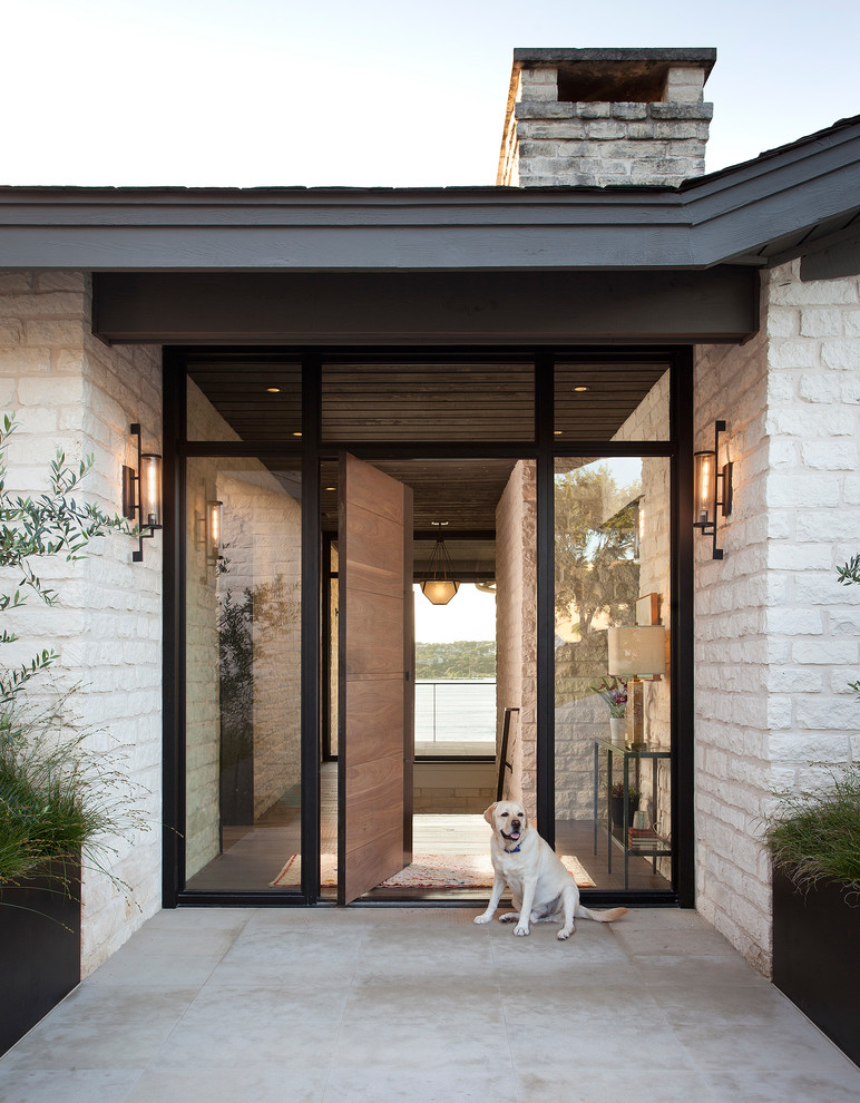 Ispirazione per una porta d'ingresso contemporanea con pareti bianche, una porta a pivot, una porta in legno bruno e pavimento grigio